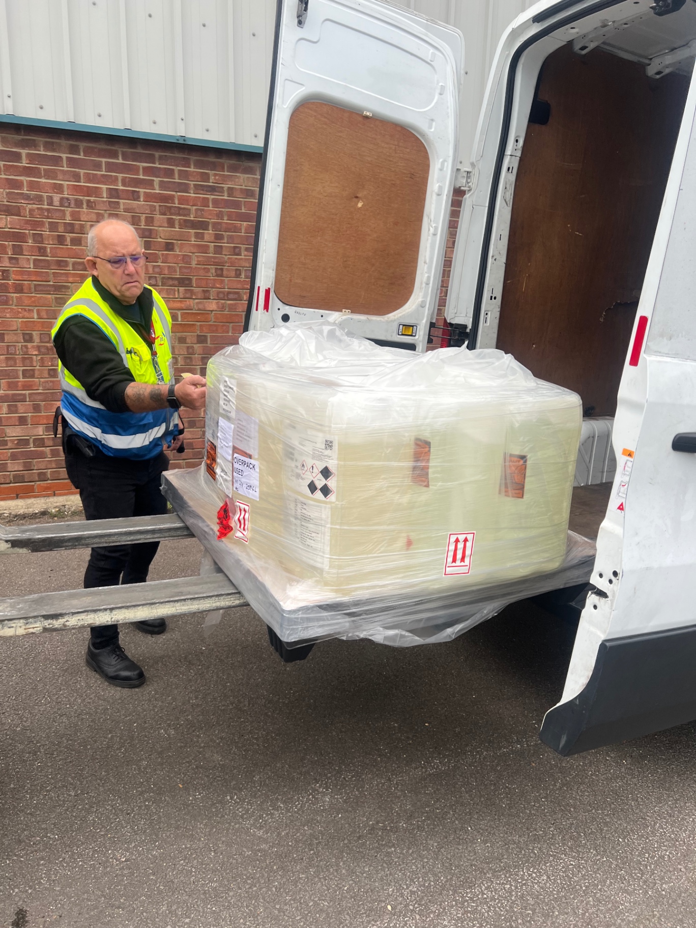Driver in hi-vis unloading pallet on tail-lift